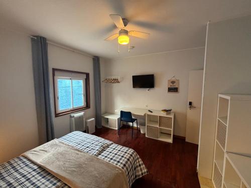 a bedroom with a bed and a desk and a ceiling fan at Casa Alba in Mindelo