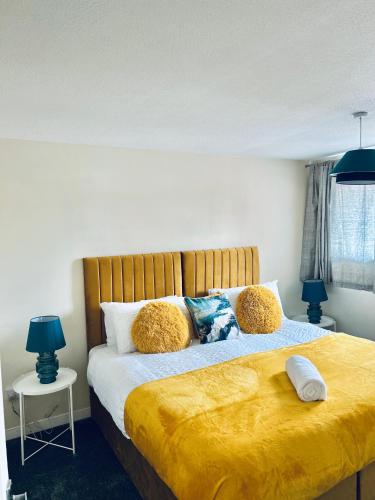 a bedroom with a large bed with yellow sheets and pillows at Spacious 3BR Home in Colchester, with Private Parking in Colchester
