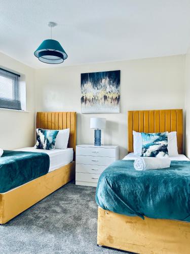 a bedroom with two beds and a night stand with a lamp at Spacious 3BR Home in Colchester, with Private Parking in Colchester