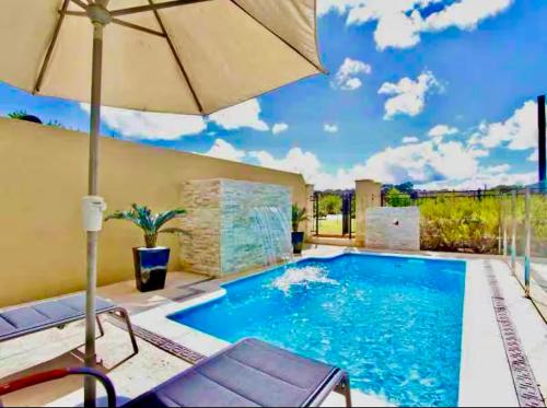 a large swimming pool with an umbrella and chairs at Luxury Villa W Pool & Spa 5 BEDROOMS in Coogee