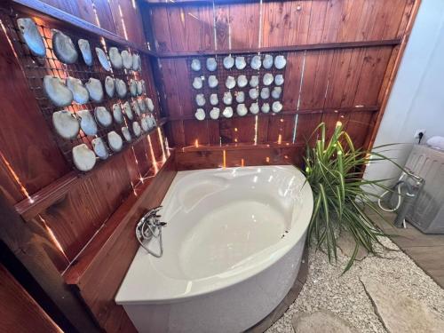 a bath tub in a bathroom with a wooden wall at Rangiroa Te Manuia Lodge in Rangiroa