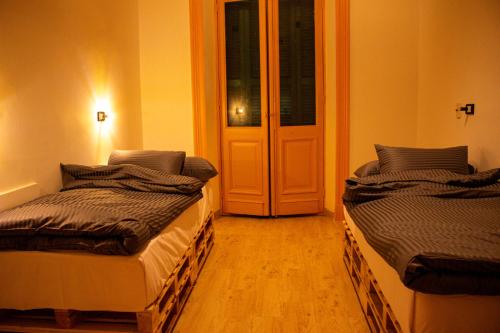 two beds in a room with a door at Ithaka Raml Hostel in Alexandria