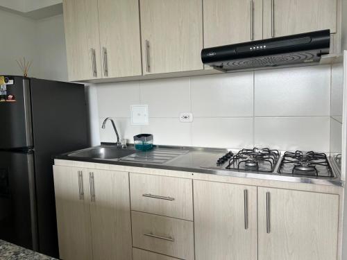 a kitchen with a stove and a black refrigerator at Apartamento TERMINAL DE TRANSPORTE, CABLE AEREO, DOLLARCITY, D1 in Manizales