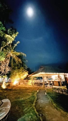 a night view of a restaurant with the moon in the sky at Kugita Bed and Dine in Moalboal