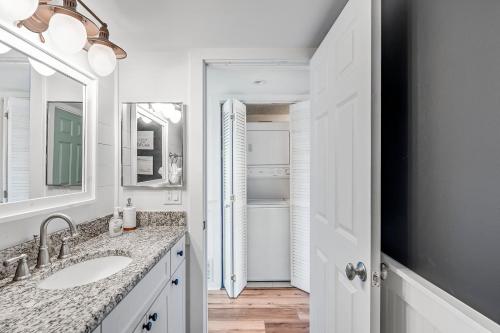 a white bathroom with a sink and a mirror at Stunning condo in Pinnacle Port, Panama City Beach in Panama City Beach