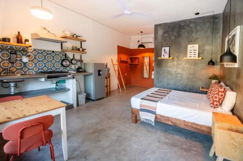 a bedroom with a bed and a table and a kitchen at Sayula HoME in Sayulita