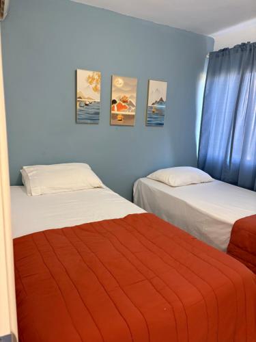 two beds in a room with blue walls at Albatros Cozy Apt in Juan Dolio