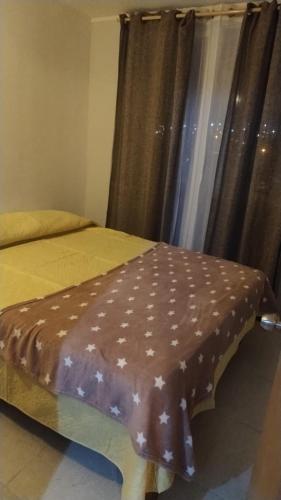 a bed with a brown cover on it with a window at Añañuca #405 in Huasco