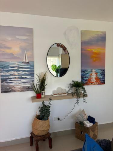 una sala de estar con pinturas en la pared y un espejo. en Albatros Cozy Apt, en Juan Dolio