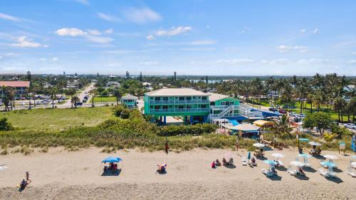 a beach with chairs and umbrellas in front of a resort at Oceanfront Inn Room #15- Inlet View- King Bed in Fort Pierce