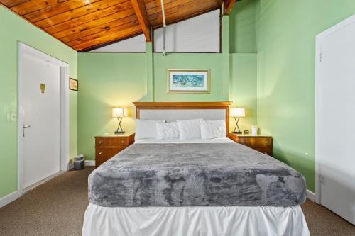a bedroom with a large bed with green walls at Oceanfront Inn Room #10- Standard Room - King Bed in Fort Pierce