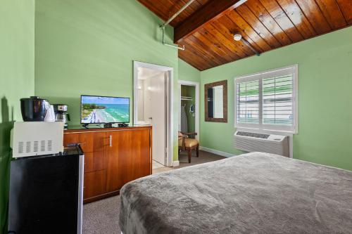 a bedroom with a bed and a flat screen tv at Oceanfront Inn Suite in Fort Pierce