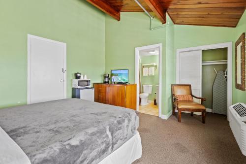 a bedroom with green walls and a bed and a chair at Oceanfront Inn Suite in Fort Pierce