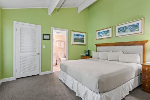 a bedroom with a large bed and green walls at Oceanfront Inn Room #11- Standard Room - King Bed in Fort Pierce