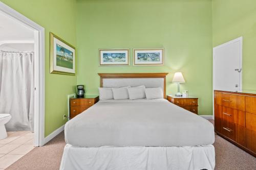 a bedroom with a white bed and green walls at Oceanfront Inn Room #11- Standard Room - King Bed in Fort Pierce