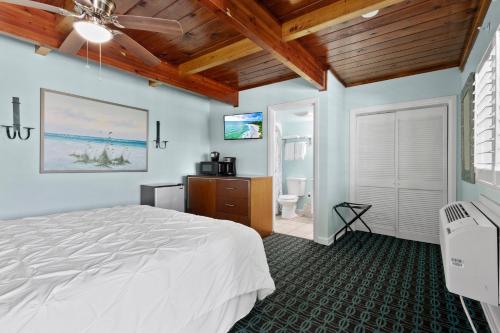 a bedroom with a white bed and a bathroom at Oceanfront Inn Room #5 - Standard Room - King Bed in Fort Pierce