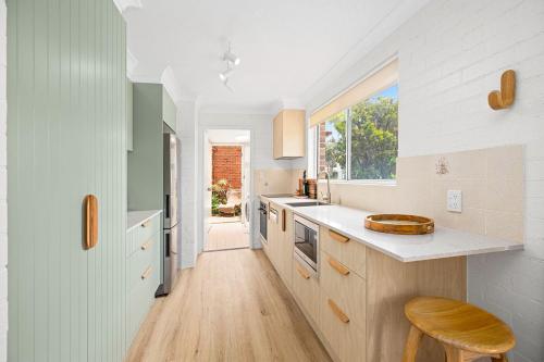 a kitchen with white counters and a wooden floor at Hoppy's Place in Sawtell