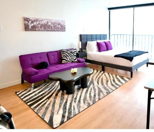 a living room with a purple couch and a bed at Salt City Haven in Salt Lake City