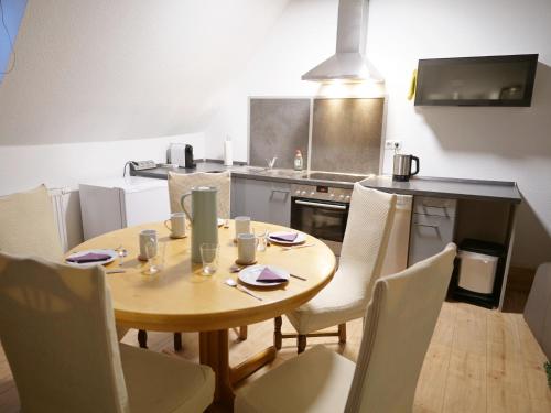 Una cocina con una mesa de madera y sillas blancas. en Albsteig-Apartments Gruibingen, en Gruibingen