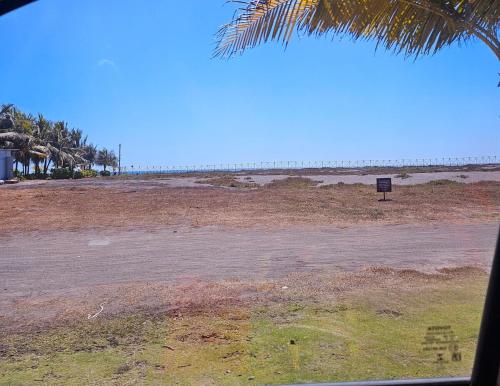 an empty beach with palm trees and a sign at Luxury Villas en Monterrico in Monterrico