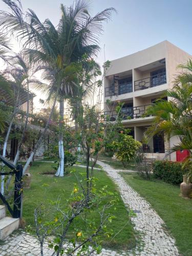 a resort with palm trees in front of a building at Pousada Aruana in Canoa Quebrada