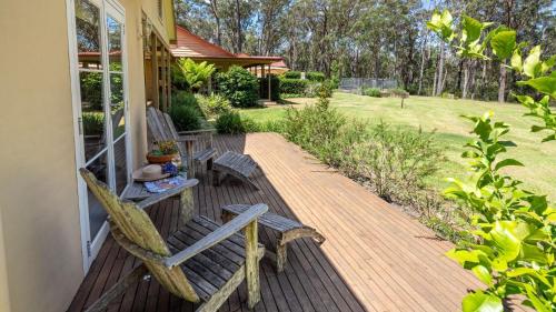 a porch with two wooden chairs and a table at Balmaghie in Bundanoon