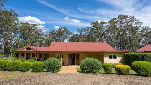 a house with a red roof and some bushes at Balmaghie in Bundanoon