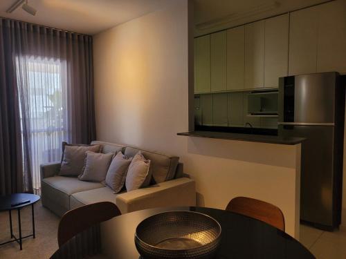een woonkamer met een bank en een tafel bij Apartamento Urbano 02 dormitórios in Marília