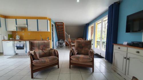 a living room with two chairs and a kitchen at Chalet Vue Lac in Chaillac