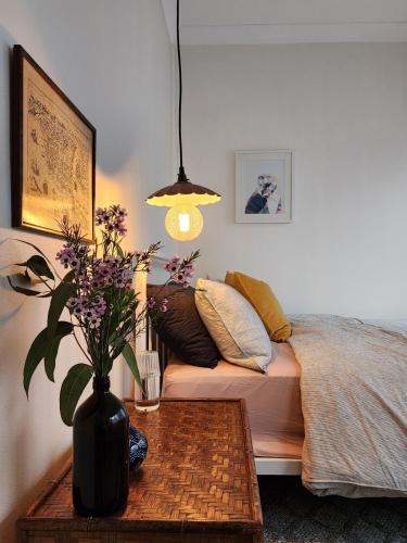 a room with a bed and a table with a vase of flowers at Country Style in the City - Close to Airport in Sydney