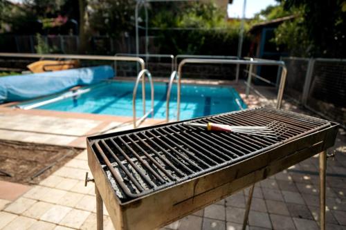 a grill sitting in front of a swimming pool at Rebeca's Family Travel Getaway! Golan! Hand-Made in Qasrîne