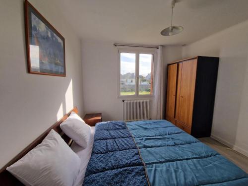 sypialnia z niebieskim łóżkiem i oknem w obiekcie Breton cottage, 500 m beach, Penvénan, Pink Granite Coast-ex TUI w mieście Penvénan