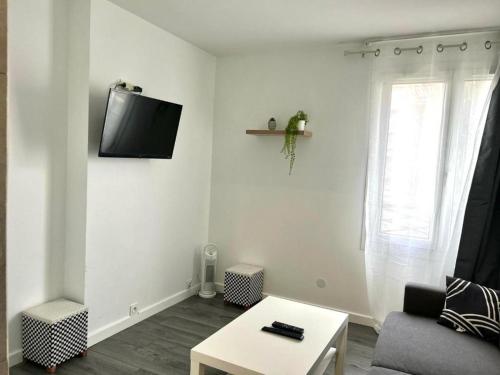 un salon avec un canapé et une télévision au mur dans l'établissement STUDIO - 4pers PROCHE GARE 10 MIN DISNEY, à Bussy-Saint-Georges
