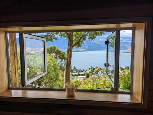 a window with a view of a lake and mountains at Greenstone Panorama - Family Bach - Stunning Views in Queenstown