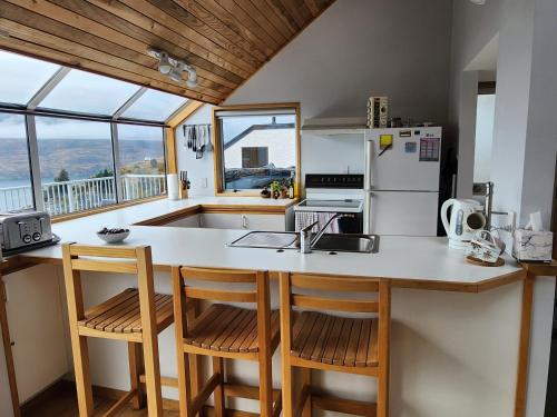 a kitchen with a counter with chairs and a sink at Greenstone Panorama - Family Bach - Stunning Views in Queenstown