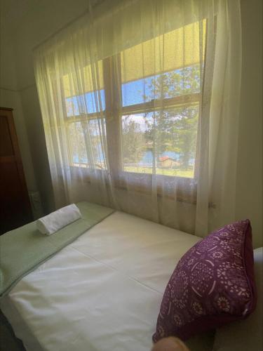 a bed in a room with a window at Mary MacKillop Spirituality Centre Central Coast in Kincumber South