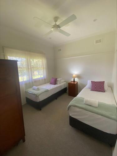 a bedroom with two beds and a ceiling fan at Mary MacKillop Spirituality Centre Central Coast in Kincumber South