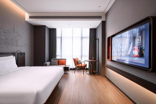 a hotel room with a bed and a flat screen tv at UrCove by HYATT Shantou Zhugang New Town in Shantou