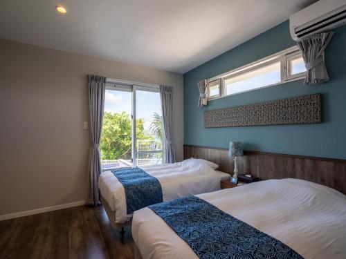 a hotel room with two beds and a window at Pool Villa The Sweet Kouri Island in Nakijin