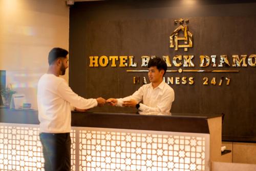 two men shaking hands over a counter in a hotel room at Hotel Black Diamond - Transit Point Inside Hotel in Kathmandu