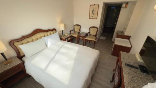 a bedroom with a white bed and a table and chairs at Hua Tong Hotel in Hualien City