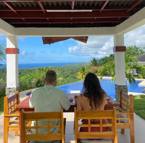 a man and woman sitting at a table looking out at the ocean at Villa MountainView Guesthouse in Dimiao