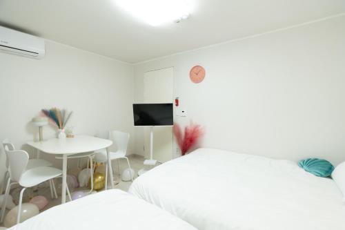 a white bedroom with two beds and a table at DDM Stay 동대문 스테이 in Seoul