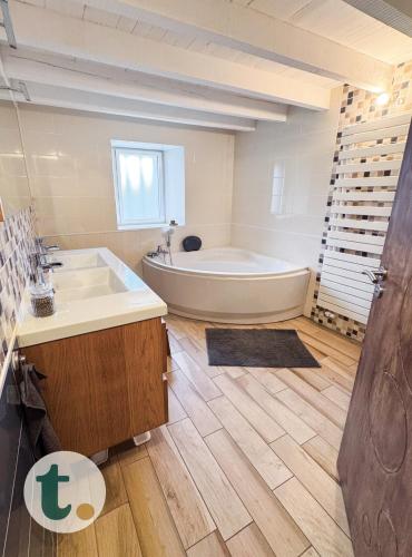 une grande salle de bain avec une baignoire et un lavabo dans l'établissement Tranquiloue - Maison spacieuse à 8min du PuyduFou, à Saint-Laurent-sur-Sèvre