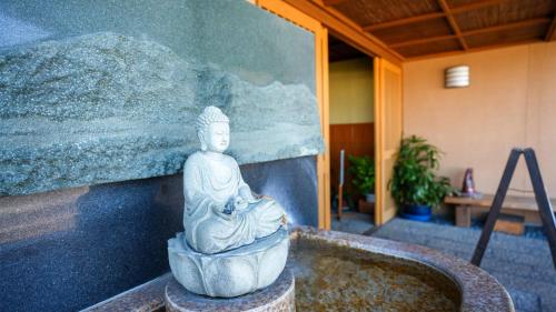 a statue of a buddha sitting on a wall at Ryokan Hirayama in Ueki