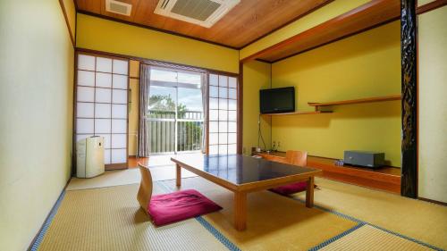 a living room with a table and a large window at Ryokan Hirayama in Ueki