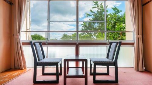 a table and two chairs in front of a window at Ryokan Hirayama in Ueki