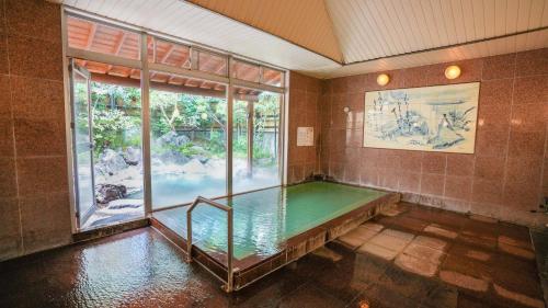 a swimming pool in a room with a large window at Ryokan Hirayama in Ueki