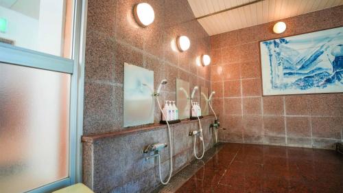 a tiled bathroom with a shower and a sink at Ryokan Hirayama in Ueki