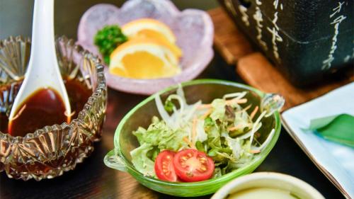 a table with a salad and a bowl of sauce at Ryokan Hirayama in Ueki